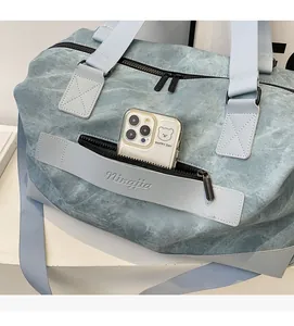 Detailed close-up of front zipper pocket on grey-blue travel bag holding a smartphone