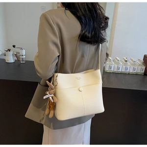 Close-up of cream-white pebbled leather bucket bag with a cute rabbit plush charm