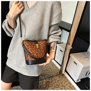 Detail of leopard print bucket bag with metal twist lock and black leather trim