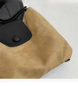 Detail of khaki suede and black leather patchwork tote bag with a round snap button