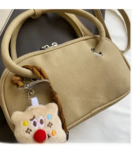 Détail d'un sac à main en daim kaki avec texture douce et pendentif ours en peluche