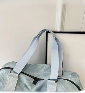 Detail of reinforced handles and metal D-rings on a large light blue travel bag
