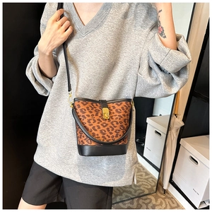 Detailed view of leopard print bucket bag with gold twist lock and black trim accents