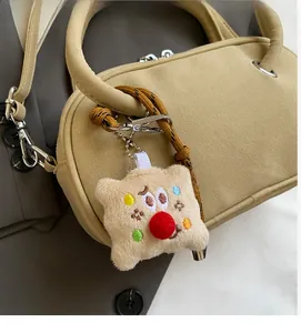 Détail d'un charm en peluche avec nez rouge sur un sac à main en cuir beige