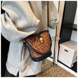Detail of leopard print bucket bag with black leather trim and golden twist lock