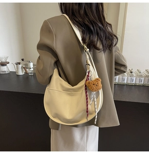 Close-up of hobo bag with pebble leather texture, bear charm and shoulder strap