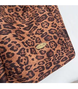 Detail of leopard print tote bag featuring a bronze metal tag with handmade engraving