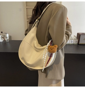 Beige hobo bag with teddy charm shown on shoulder for casual street style