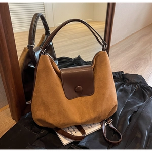 Close-up of retro brown suede and leather tote bag showing texture and mirror reflection