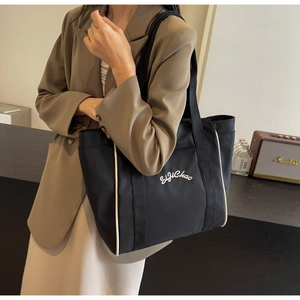 Detalle de un bolso tote grande de lona negra con ribetes blancos y bordado de SijiChao