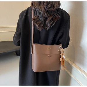 Brown lychee leather bucket bag with gold lettering and cute bunny charm on model