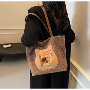 Dettaglio borsa tote in velluto a coste marrone con patch gatto arancione e manici in pelle