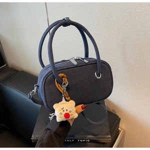 Détail du sac à main bleu foncé givré avec pompon en peluche et fermeture éclair argentée