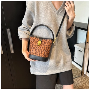 Detail showing leopard print bucket bag with gold lock and black leather handle