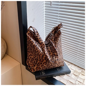 Detail of leopard print tote bag with knotted strap resting on art books under soft light