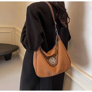 Detail of caramel brown hobo bag featuring silver chain and round M-logo hardware
