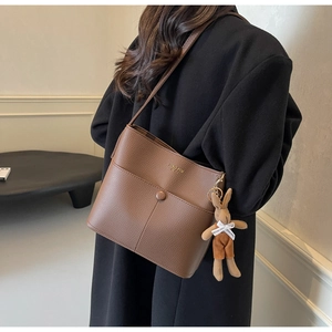 Brown litchi grain leather bucket bag with gold lettering and cute plush bunny charm