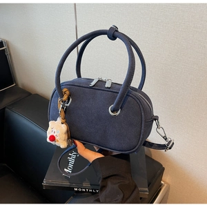 Détail du sac bandoulière givré bleu marine avec fermeture éclair et charm d'ours