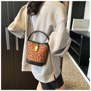 Detail of leopard print bucket bag featuring a gold twist lock and black leather trim