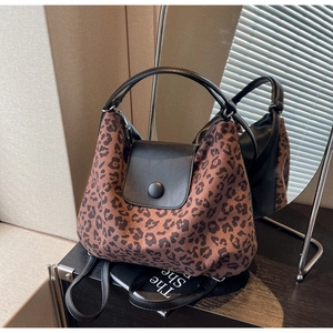Detail of leopard print tote bag with black leather patchwork and round decorative buckle