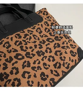 Close-up of leopard print fabric texture and black leather handle stitching detail