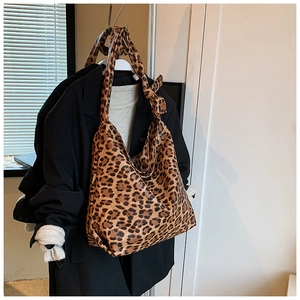 Detail of leopard print canvas tote bag featuring a stylish knotted shoulder strap design