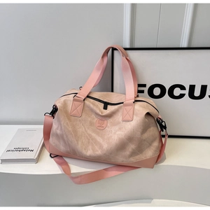 Macro shot of pink suede-textured travel bag featuring embossed logo and durable handles
