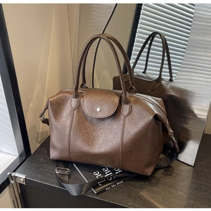 Close-up of retro brown embossed leather handbag with double handles and wide strap