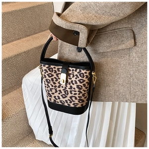 Detail of leopard print bucket bag with gold hardware worn with a brown blazer