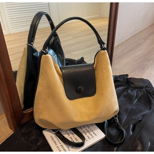 Detailed close-up of the yellow suede and black leather tote bag with round buckle detail