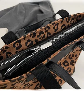Detailed close-up showing the smooth silver metal zipper and leopard print fabric texture