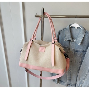Détail du sac de voyage en toile avec garniture en cuir rose et bandoulière réglable