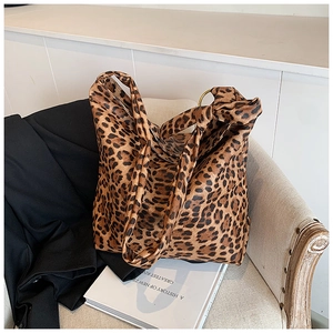 Close-up of leopard print canvas tote bag featuring golden metal ring and rolled handle