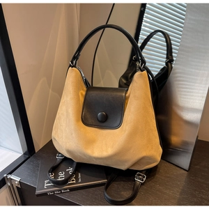 Detail of khaki suede and black leather tote bag with round snap button on mirrored stand
