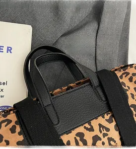 Detail of leopard print bucket bag featuring lychee grain leather handle and fabric strap