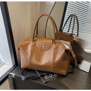 Close-up of vintage brown leather tote with a stylish logo strap and rustic texture
