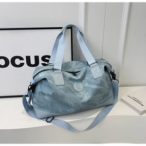 Detail view of the blue washed canvas travel bag on a white display stand with focus on texture