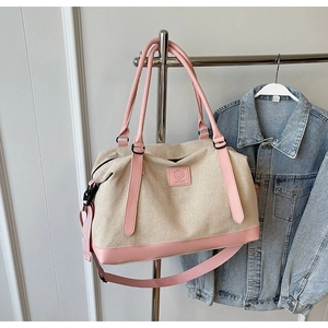 Détail du grand sac de voyage en toile beige avec bordure en cuir rose sur un cintre