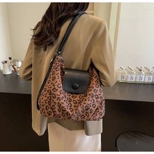 Detail view of leopard print hobo bag with a black leather flap and button
