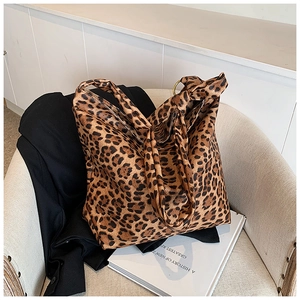 Detail shot of leopard print tote bag on a white armchair with a black blazer accent