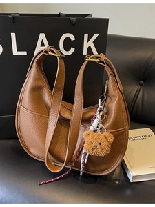 Brown lychee leather crescent bag with teddy bear charm and adjustable strap
