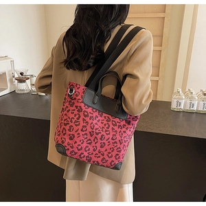 Detail of red leopard print tote with black leather trim and wide adjustable shoulder strap
