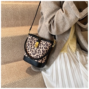 Detail of leopard print bucket bag featuring black leather trim and golden metal clasp lock
