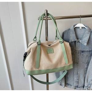 Détail du grand sac de voyage en toile avec finitions en cuir vert menthe sur cintre