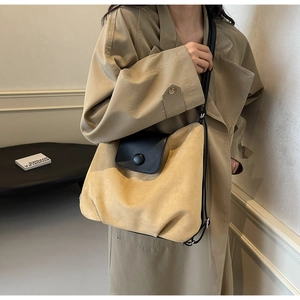 Close-up of retro camel suede tote bag with black leather flap on a khaki trench coat