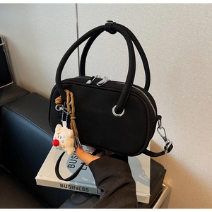 Détail d'un sac à main noir givré vintage avec breloque ours et détails en métal argenté