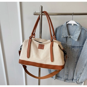Détail du sac de voyage en toile avec finitions cuir, logo et bandoulière réglable pratique