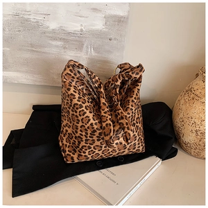 Detail of leopard print canvas tote bag placed on a suit jacket with aesthetic props