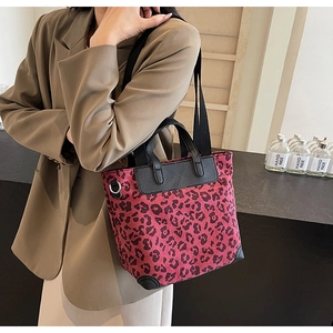 Detail of red and black leopard print tote bag with leather strap on model shoulder