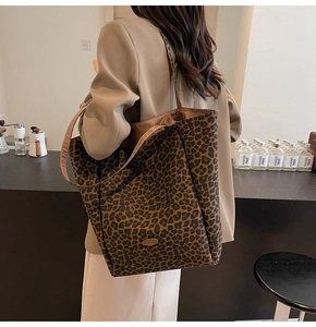 Detailed shoulder view of a large leopard print tote bag with metallic oval logo plaque